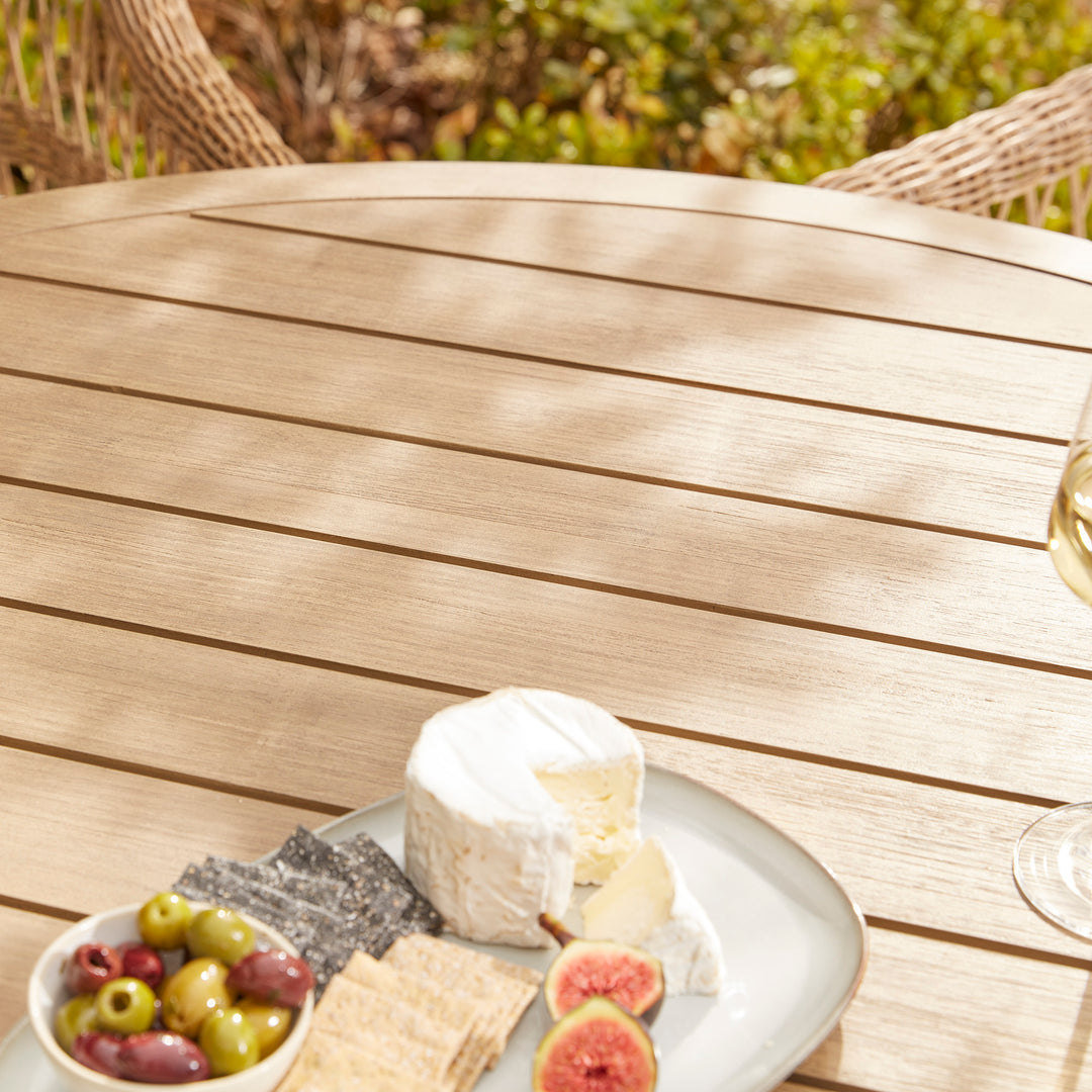 A solid acacia wood garden dining table to seat four, laid for casual drinks and nibbles