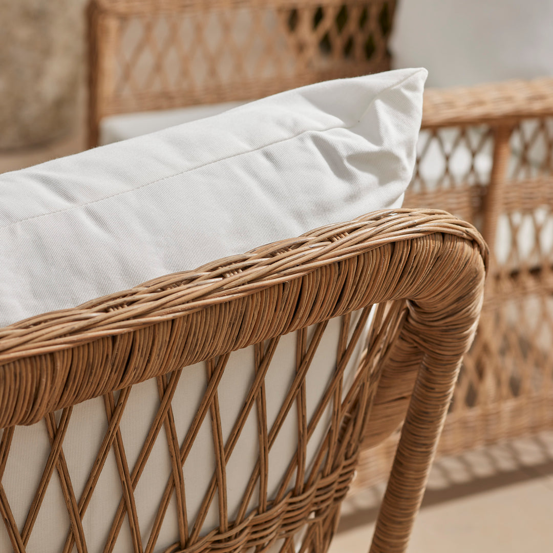 Close-up of and elegant wicker sofa from the back, showing the beautiful lattice open weave pattern.