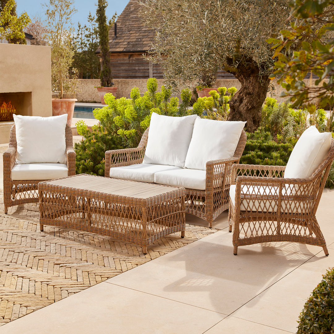 Stylish four seater compact lounge set for intimate family gatherings and all day lounging, set on a patio surrounded by structured greenery.