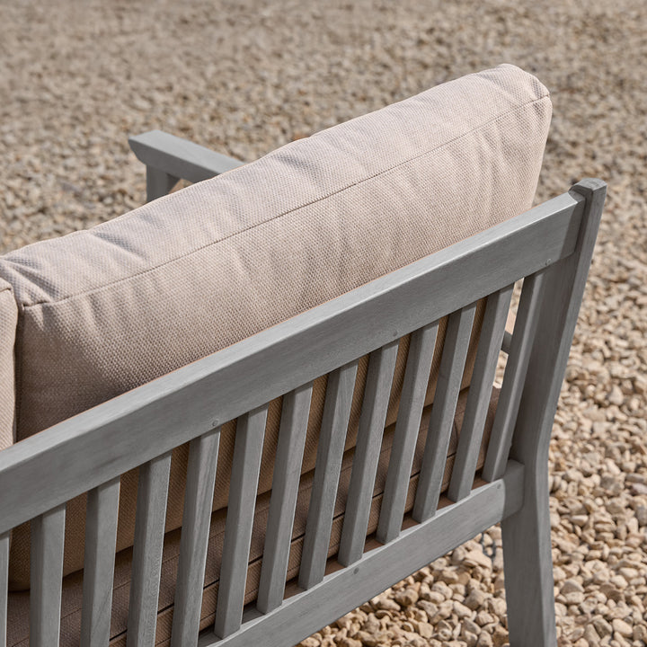Wooden sofa slatted detail with beige cushion on a gravel surface