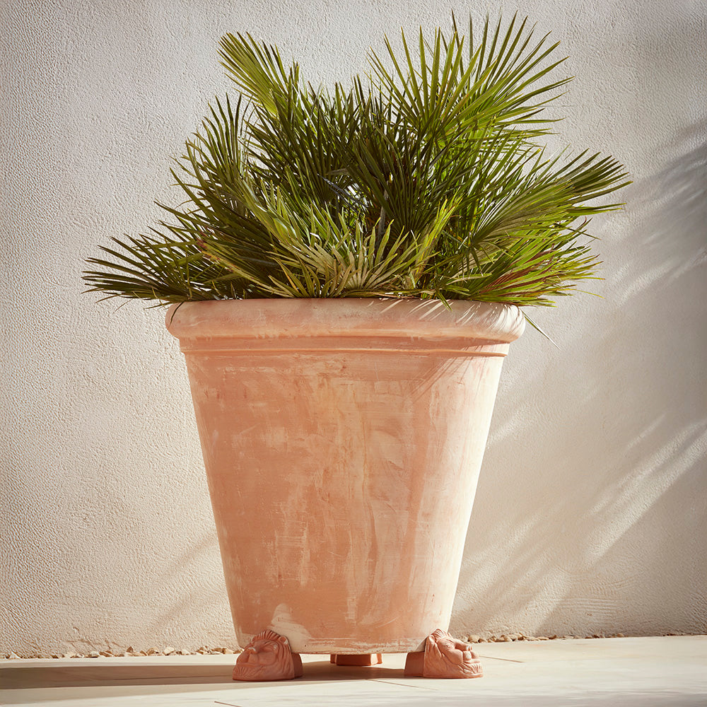 Set of three lions head pot feet holding up a 90cm terracotta plant pot. A Mediterranean scene