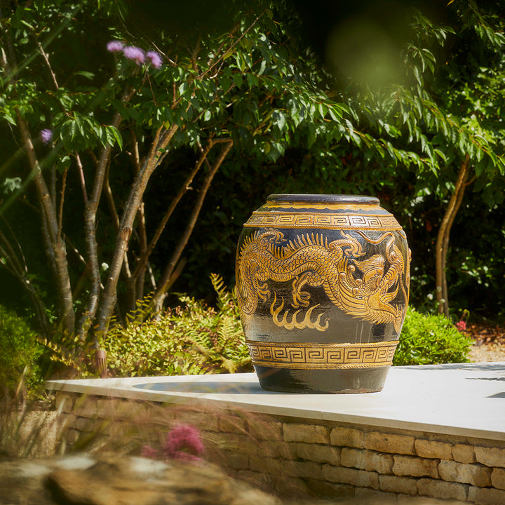 Large garden jar pot with detailed dragon motif, placed outdoors on a cotswold stone patio