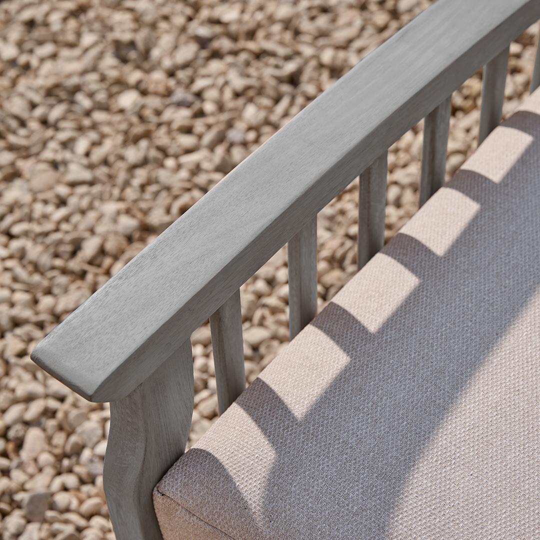 Wooden chair with a water repellant oatmeal cushion against a gravel background