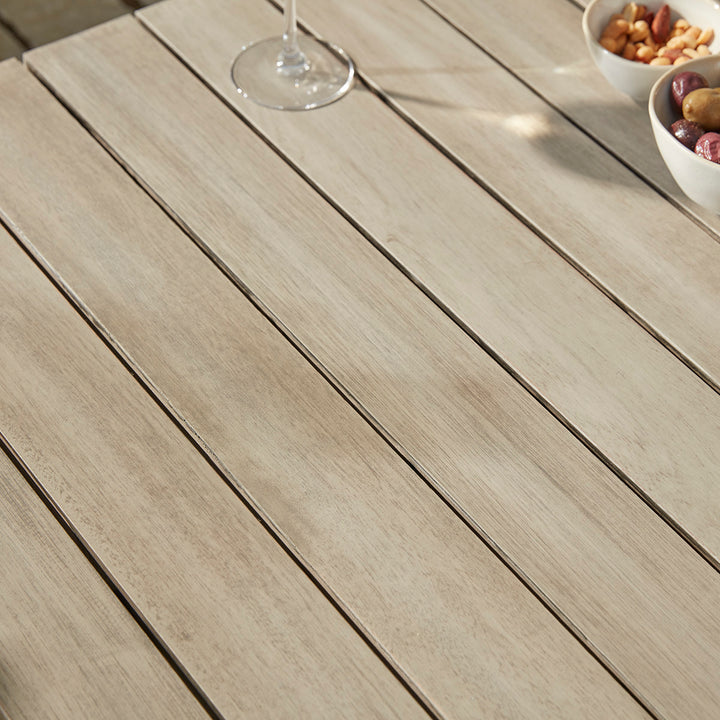 Close-up of the Repton Classic Wooden Garden Coffee Table, highlighting its slatted eucalyptus wood surface with a weathered finish. Styled with a glass of white wine and bowls of nuts and olives, this durable outdoor table is perfect for patios, garden seating, and alfresco dining.