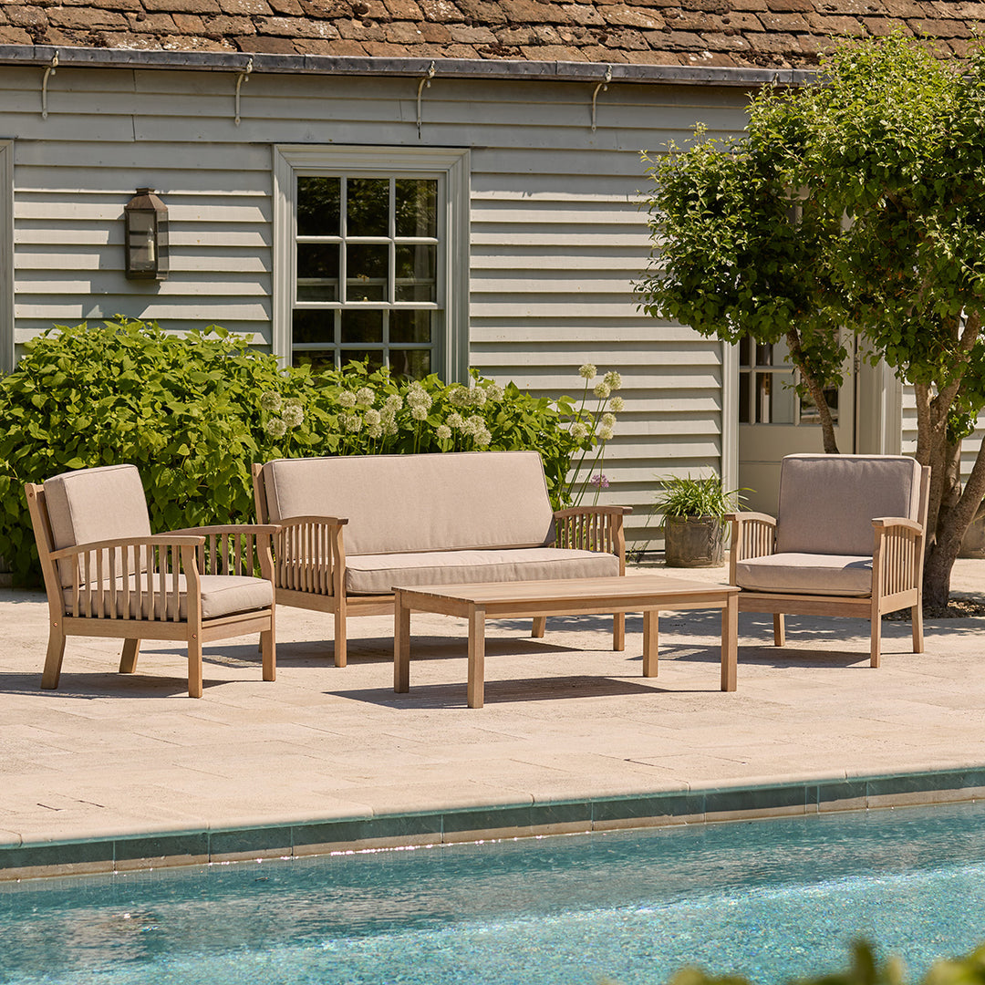 Outdoor patio set with chairs and sofa by a poolside.