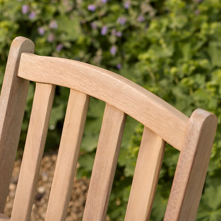 Close-up of a wooden bench seat with a blurred green garden background