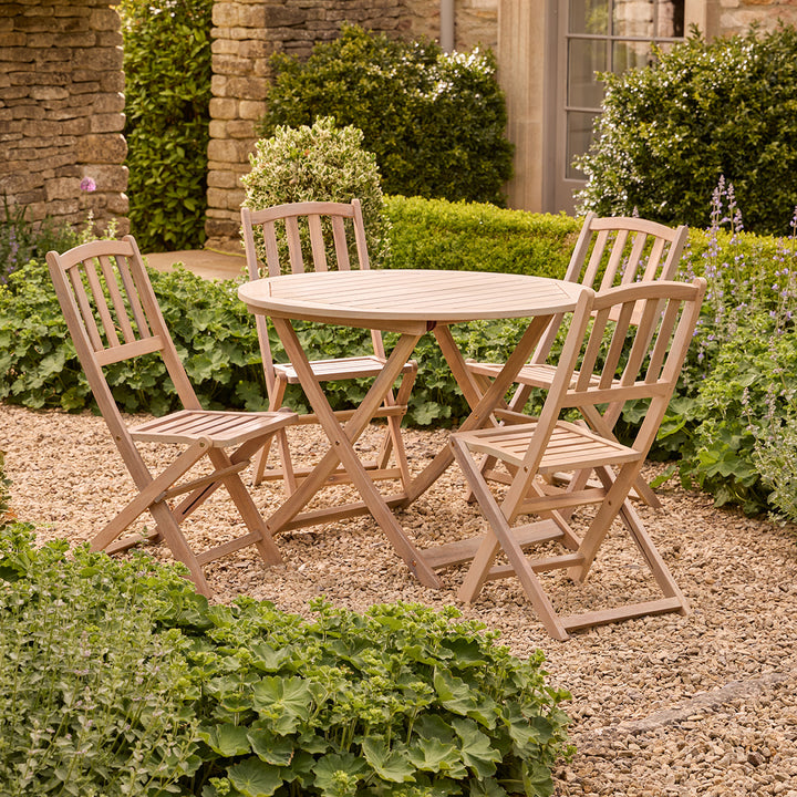 Wooden outdoor table and chairs set in a garden setting with greenery.