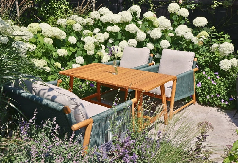 Stanley acacia wood and rope casual dining set place amongst the planting