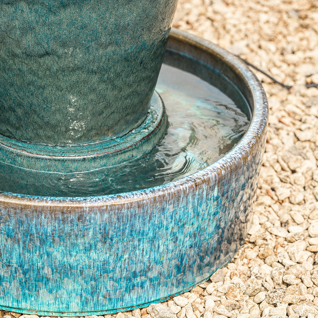 Tall blue urn water feature with high shine finish, set in a landscaped garden patio.