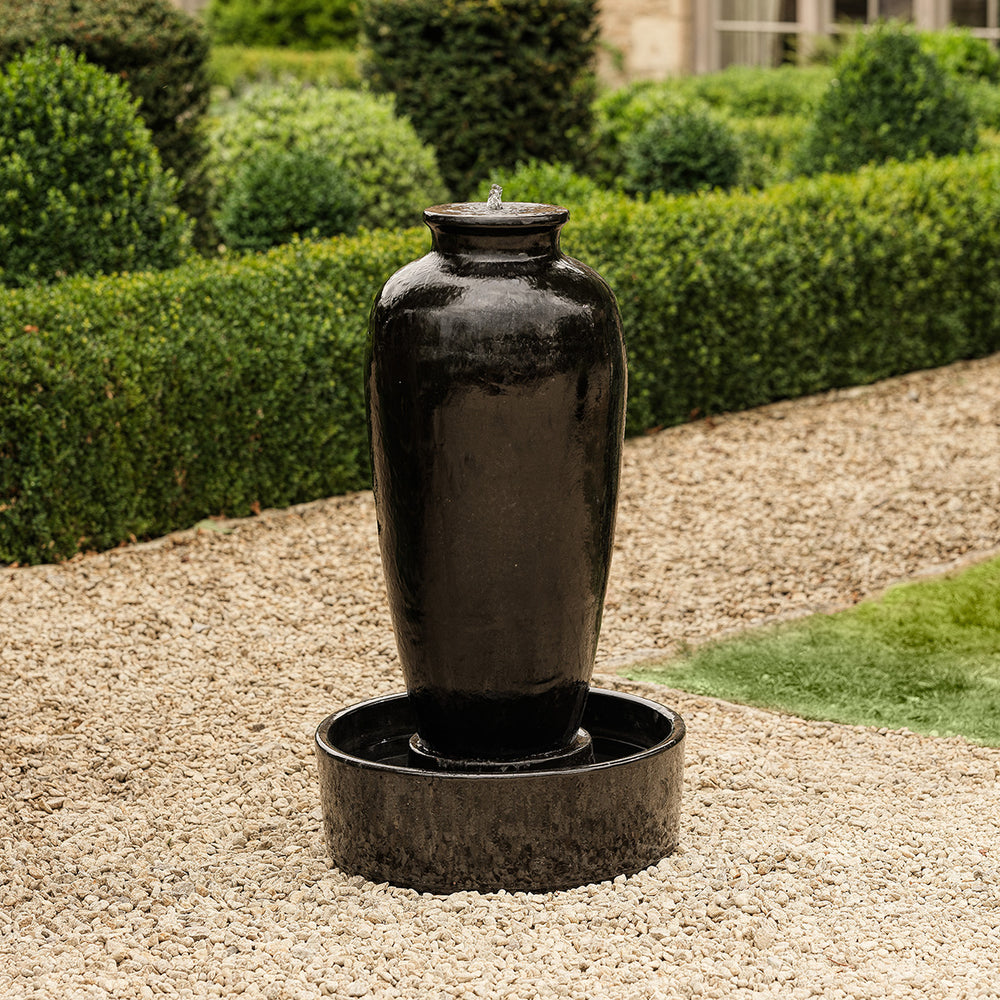 Tall black urn water feature with high gloss glaze, creating a striking garden focal point.