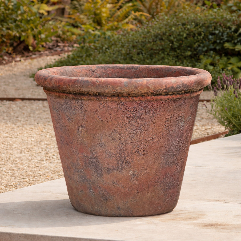 Rustic terracotta pot on a cotswold patio with a garden background