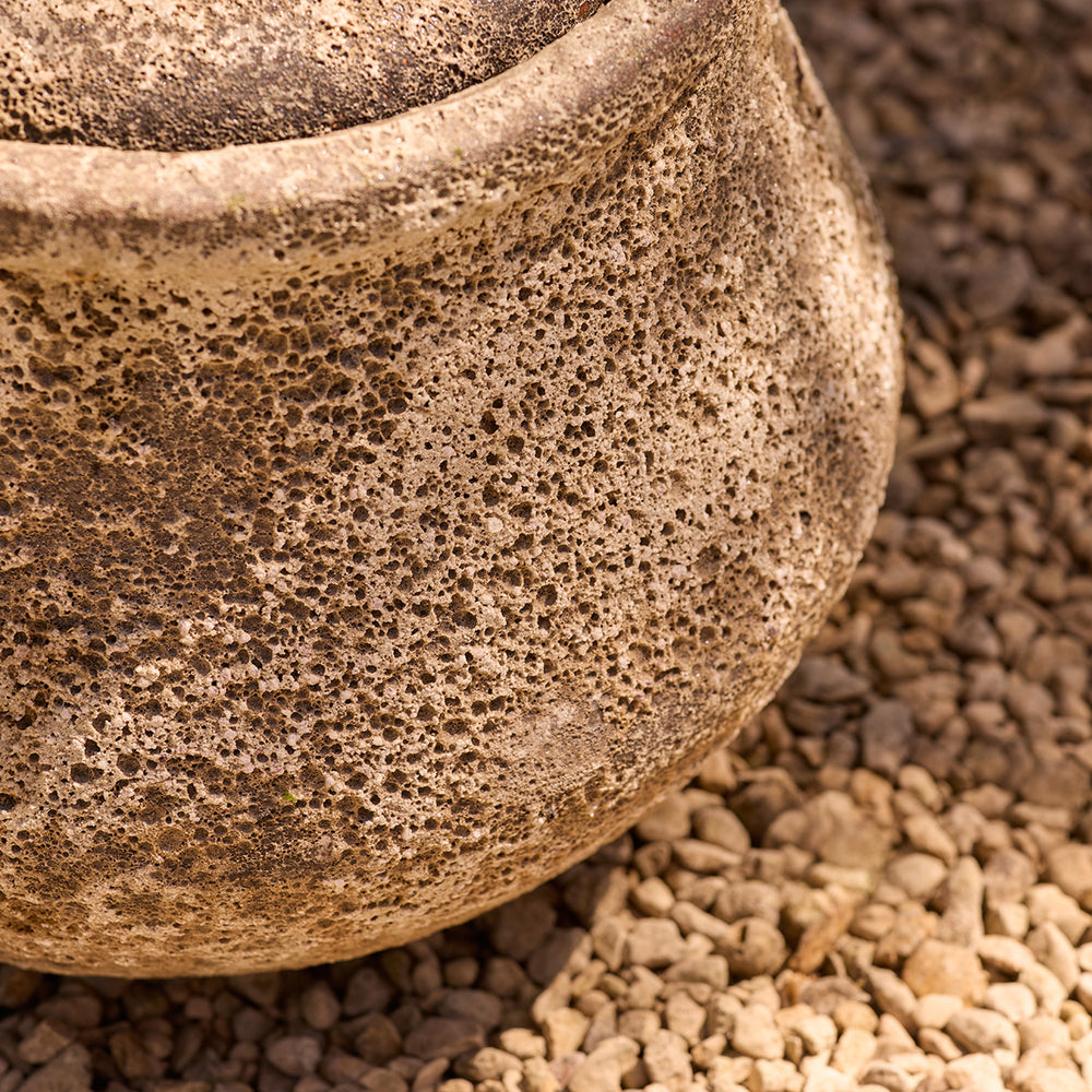 Close-up of a textured stone garden water feature on a gravel surface