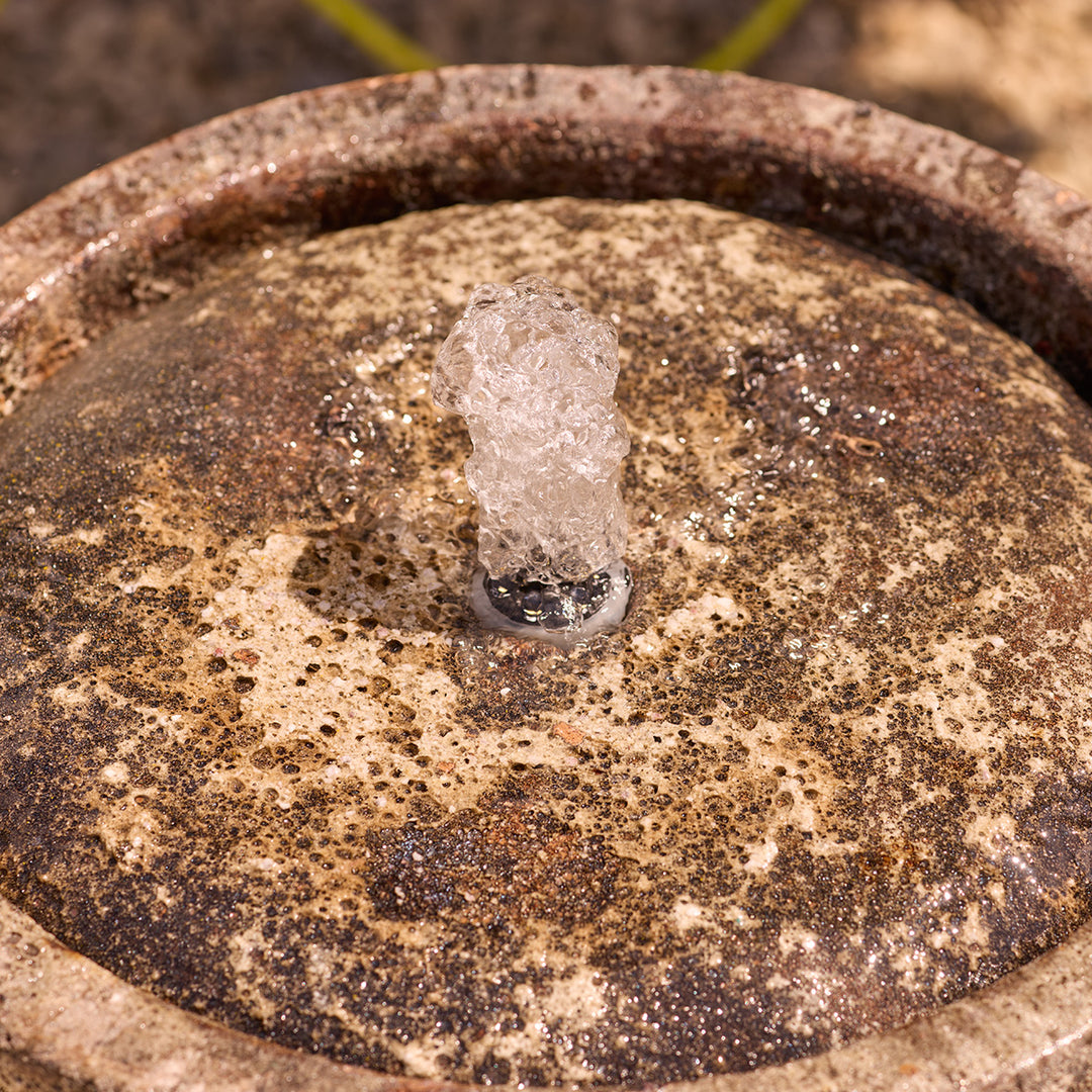 Close-up of a textured stone surface of water feature, showing the water fountain with light