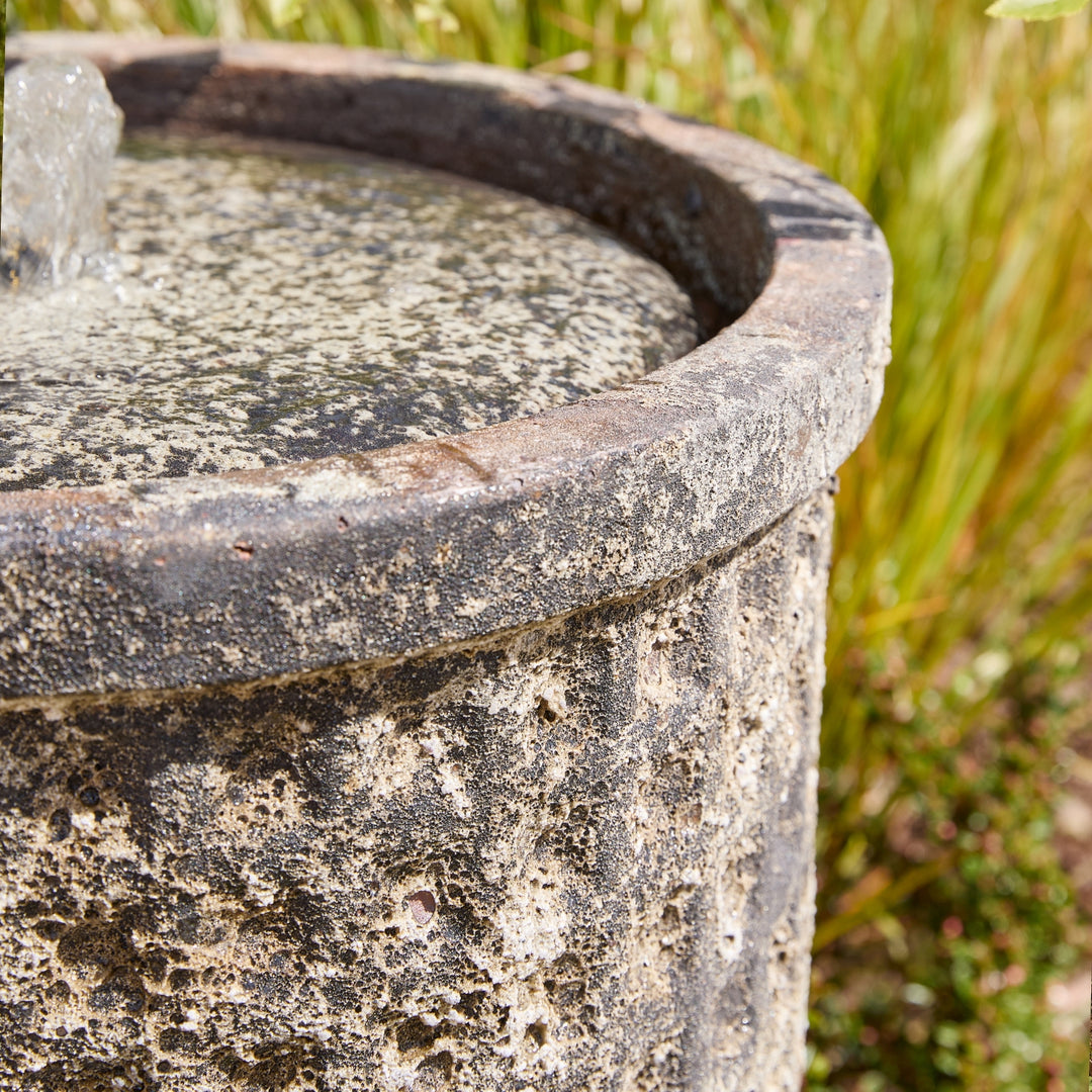 Close-up of a stone water fountain with grass in the background