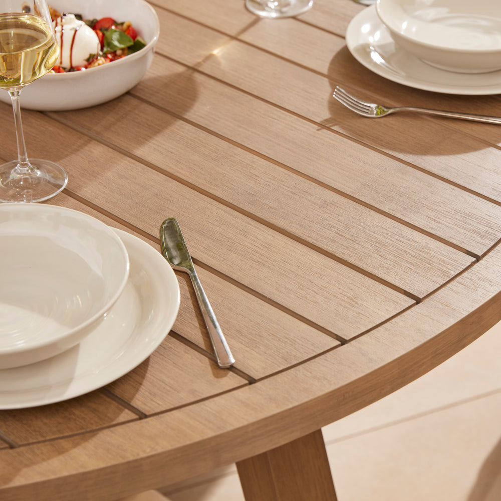 A solid acacia wood garden dining table to seat six, laid for casual summer  lunch