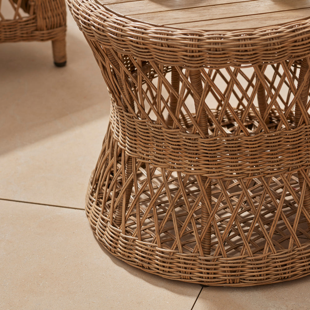 Detail of beautiful hand woven open weave rattan round side table design on a cotswold terrace patio 