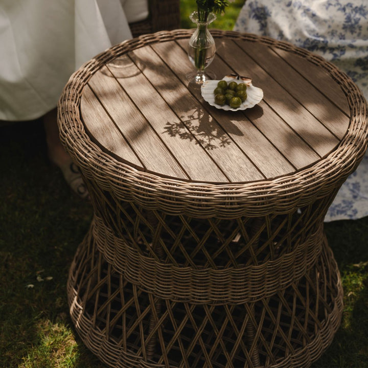 Wicker side table with a small plate of fruit on grass