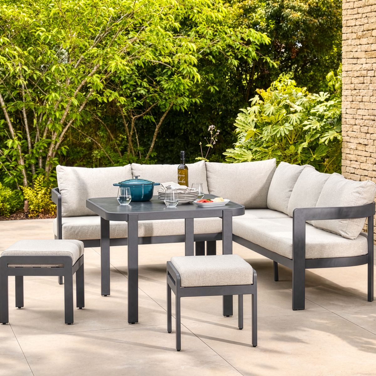 Anthracite aluminium corner dining set with cream cushions and matching stools on a modern patio