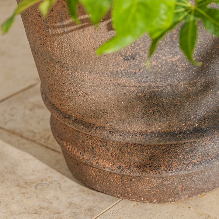 Detail of the base of an extra large terracotta garden pot with natural stone texture, crafted for planting trees and larger shrubs in outdoor spaces.