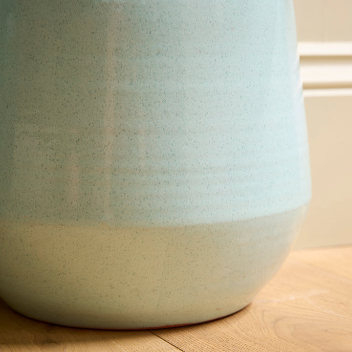 Close-up of a ceramic blue indoor plant pot with two-tone design on a wooden surface.