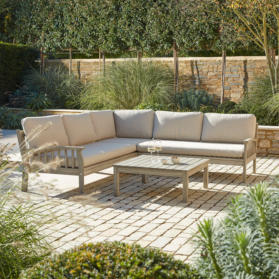 Repton Classic Corner Garden Furniture Set – a wooden outdoor corner sofa with beige cushions, designed for patios and stylish garden seating. This weather-resistant L-shaped sofa set includes a matching wooden coffee table, perfect for outdoor lounging and alfresco gatherings.