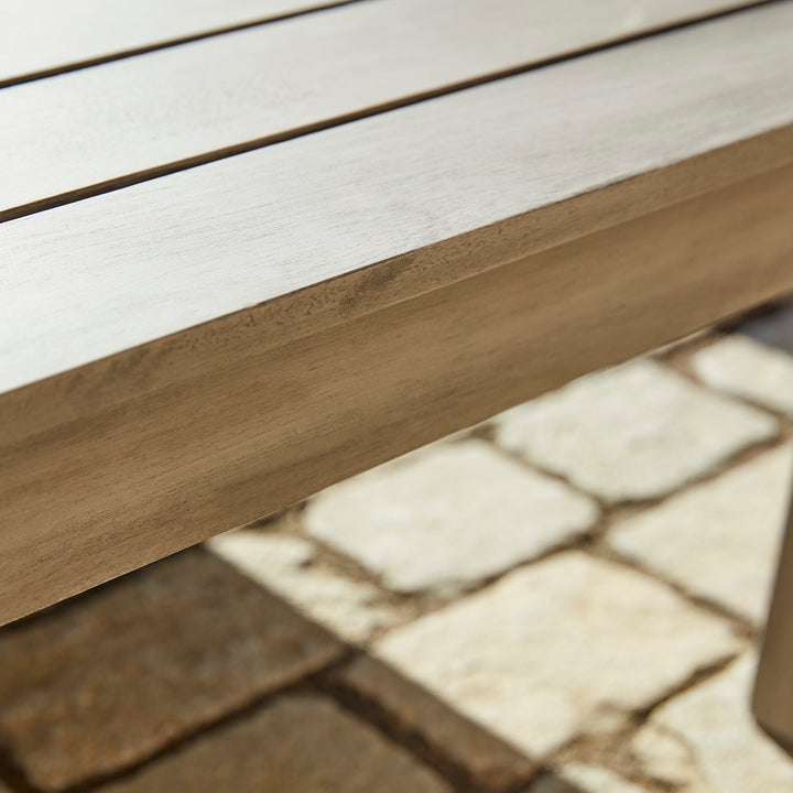Close-up of a wooden bench with a white seat on a stone pavement