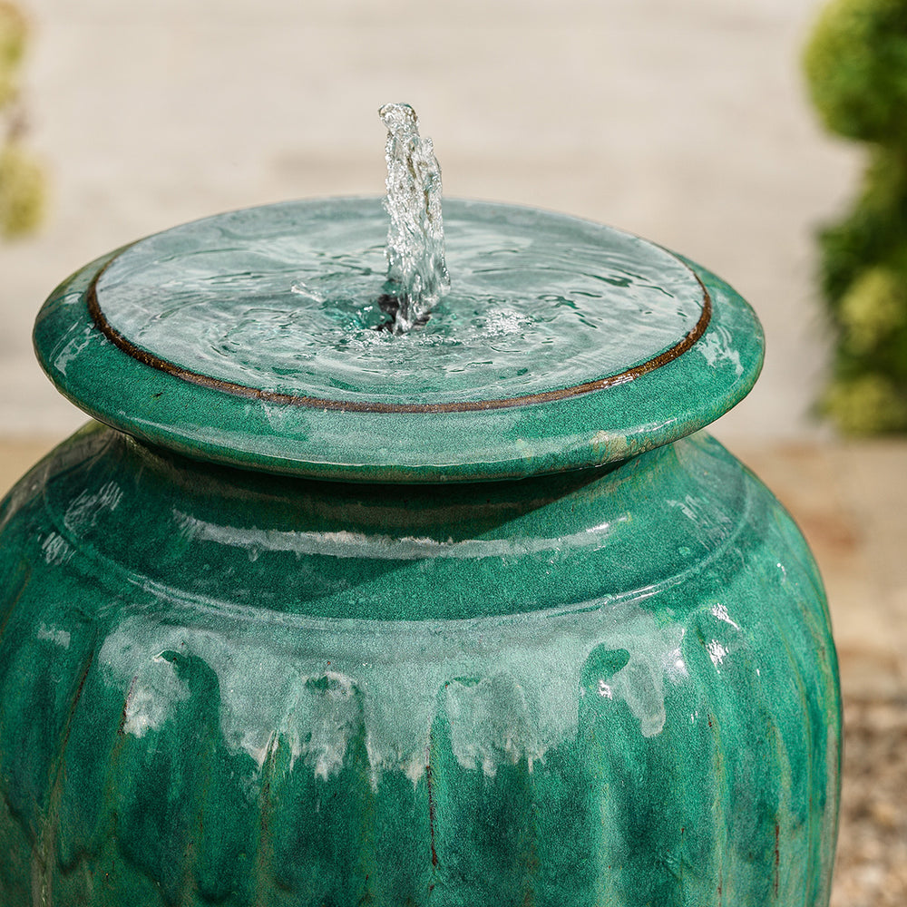 Close-up of water bubbling from the top of green urn water feature with built-in LED light.