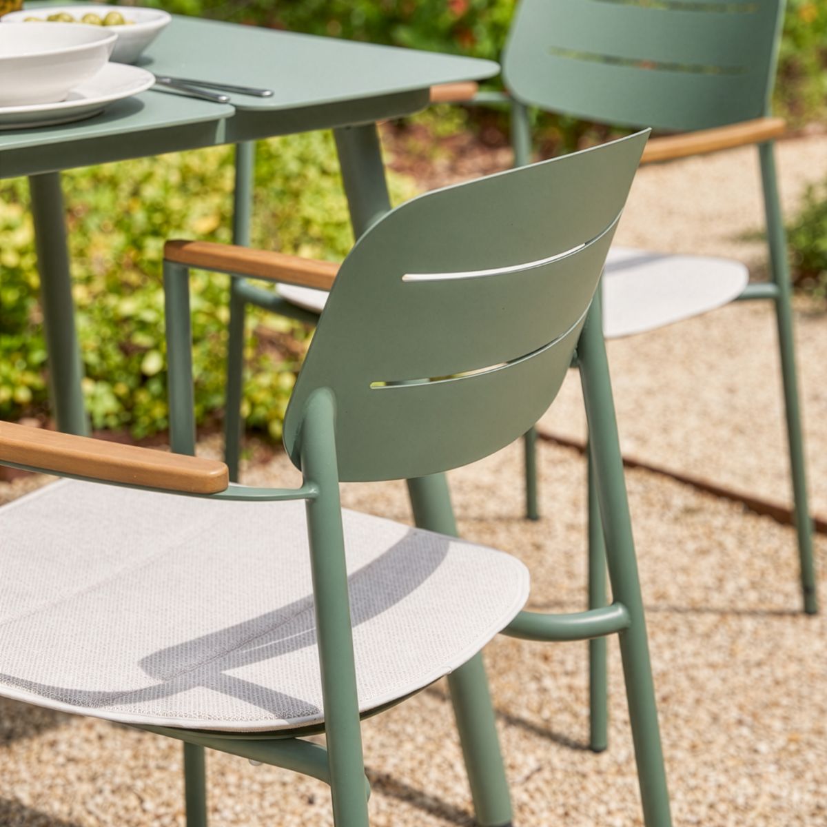 Powder-coated steel garden dining chair with slim architectural frame and natural wood armrests