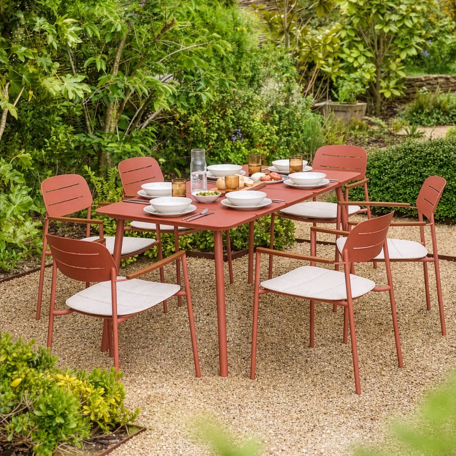 Modern six seater outdoor dining set in earthy red powder-coated steel with cream seat cushions