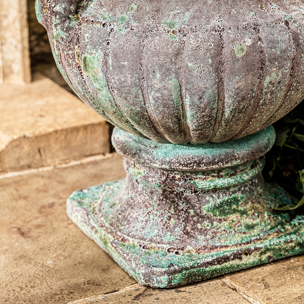 Close-up of large urn planter in turquoise finish with ribbed base and weathered patina.