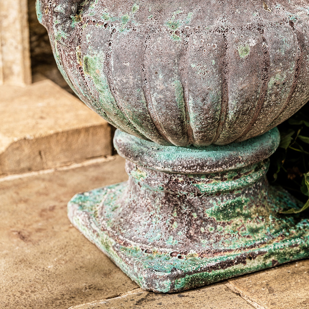 Close-up of large urn planter in turquoise finish with ribbed base and weathered patina.