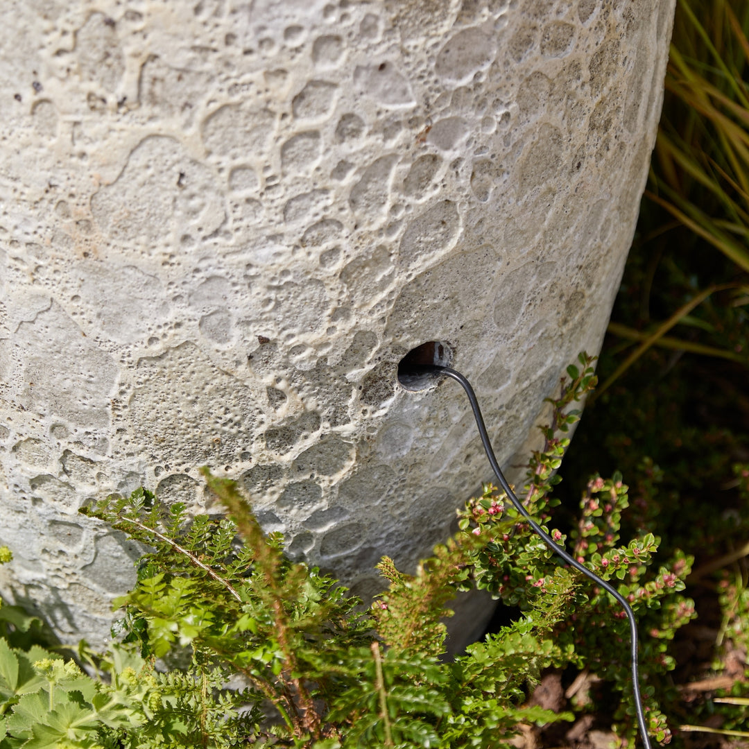 Cable entry point on water feature one third up, surrounded by greenery