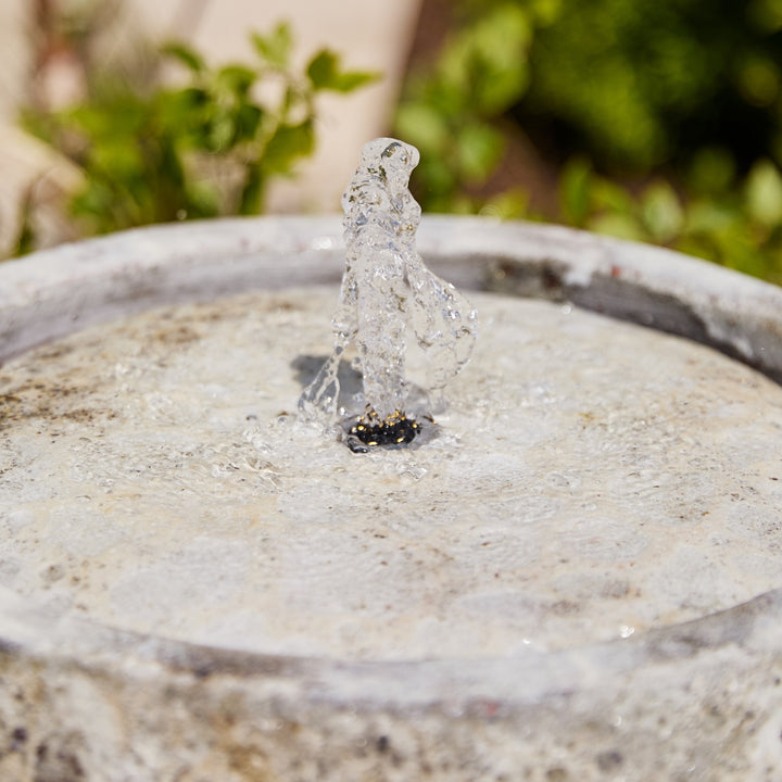 Small water fountain with water droplets on a stone surface with LED light