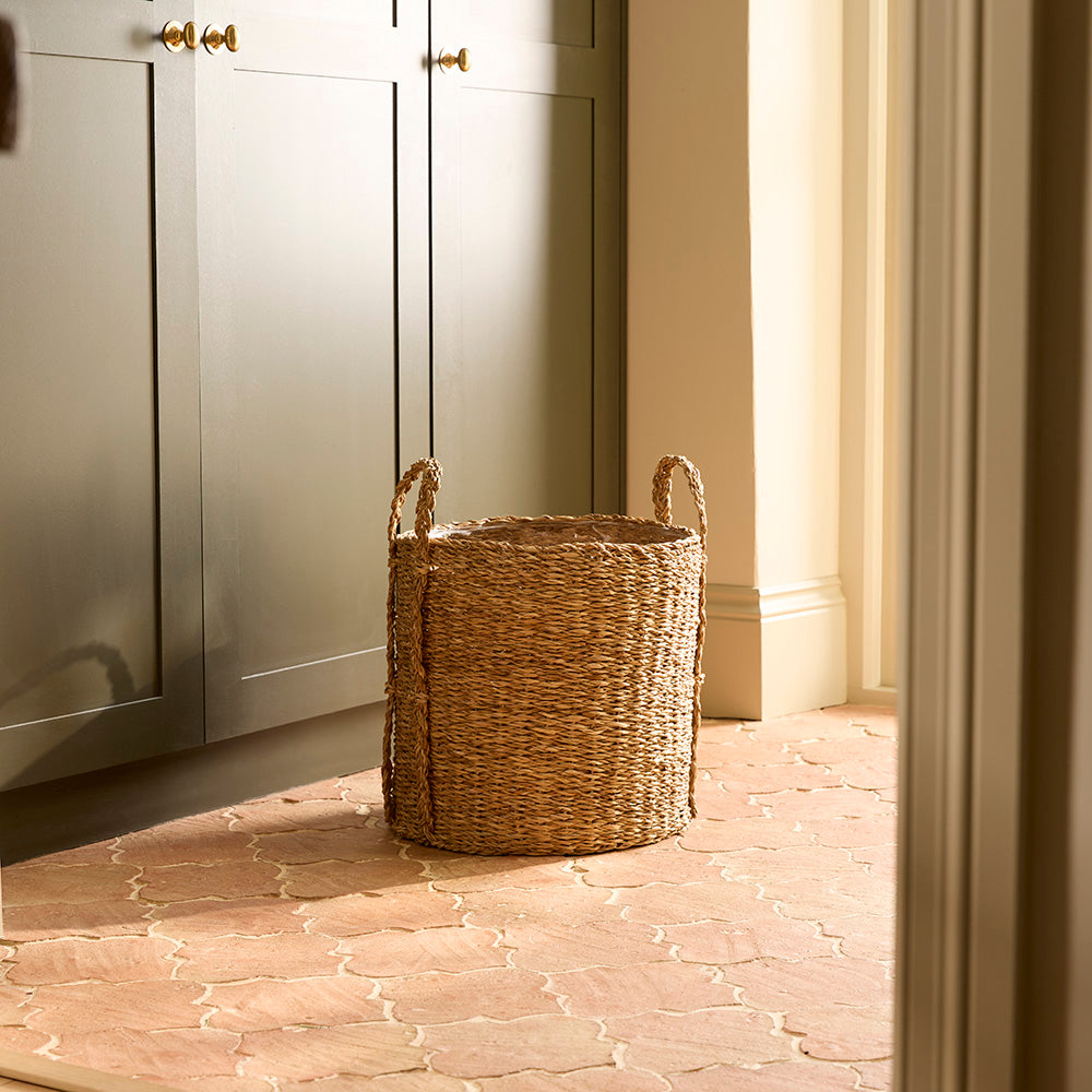 Woven basket on a stone floor with light-colored walls and cabinets.