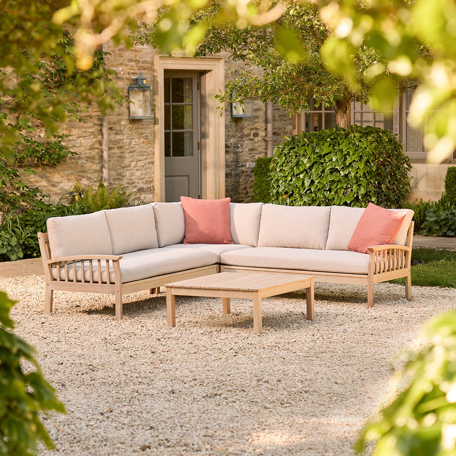 Repton Classic Corner Garden Furniture Set in a natural teak wood colour – a wooden outdoor corner sofa with beige cushions, designed for patios and stylish garden seating. This weather-resistant L-shaped sofa set includes a matching wooden coffee table, perfect for outdoor lounging and alfresco gatherings.