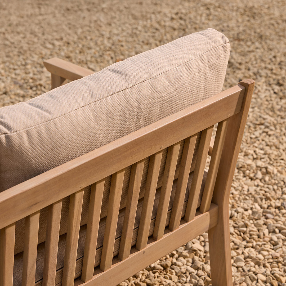 Wooden sofa slatted detail with beige cushion on a gravel surface