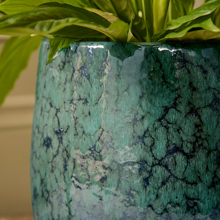 Green marbled pot with a plant, blurred background