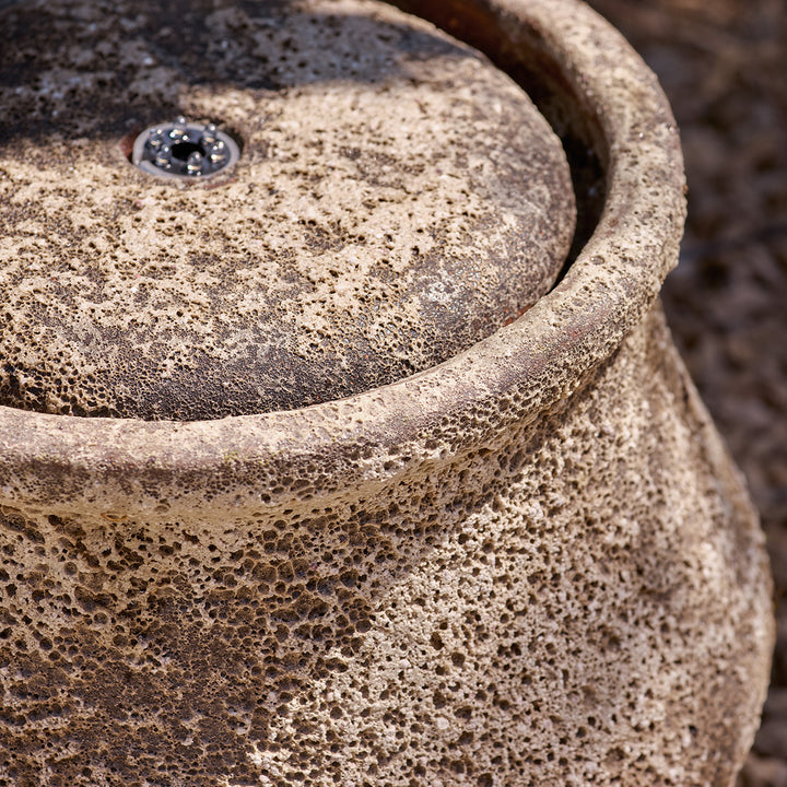 Close-up of a textured stone surface of water feature, showing the water fountain with light