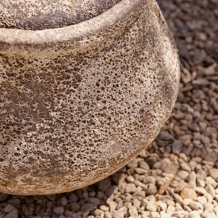 Close-up of a textured stone garden water feature on a gravel surface