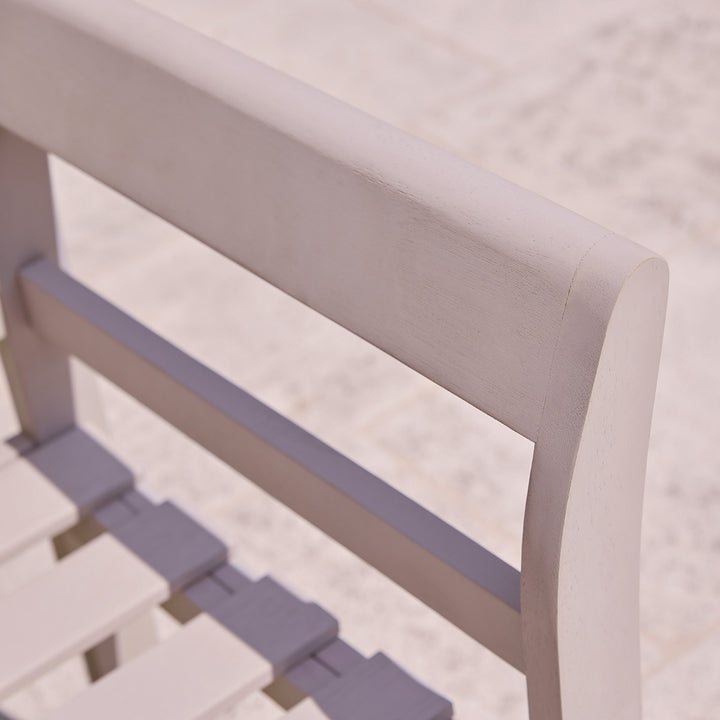 Detail of curved armrest and back slats onlight grey painted wooden garden bench, showing painted eucalyptus grain and frame strength.