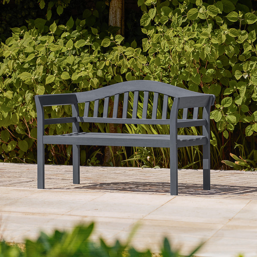 Charcoal grey wooden garden bench with traditional curved backrest and arms, styled on a small garden patio.