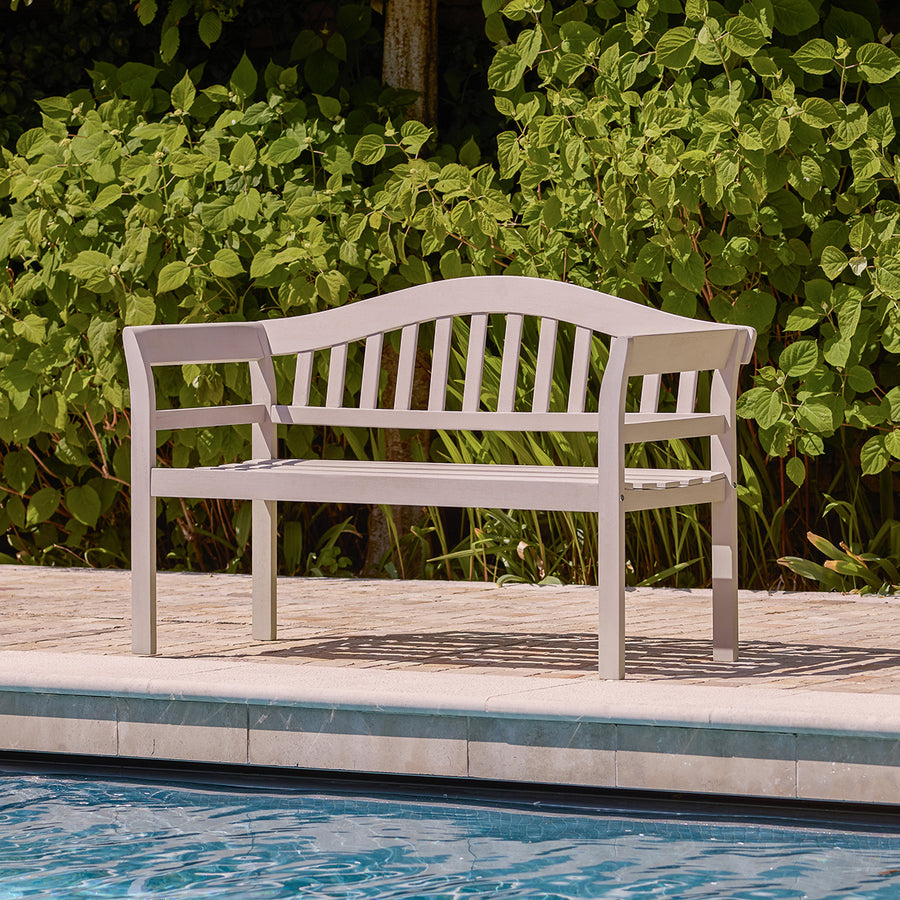 Light grey wooden garden bench with arched backrest and vertical slats, styled outdoors.