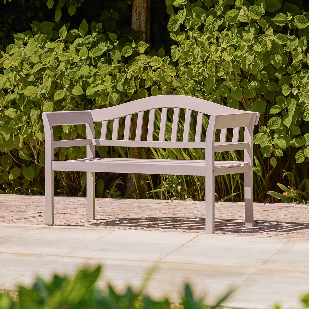 Grey painted wooden garden bench with traditional curved backrest and arms, styled on a small garden patio.