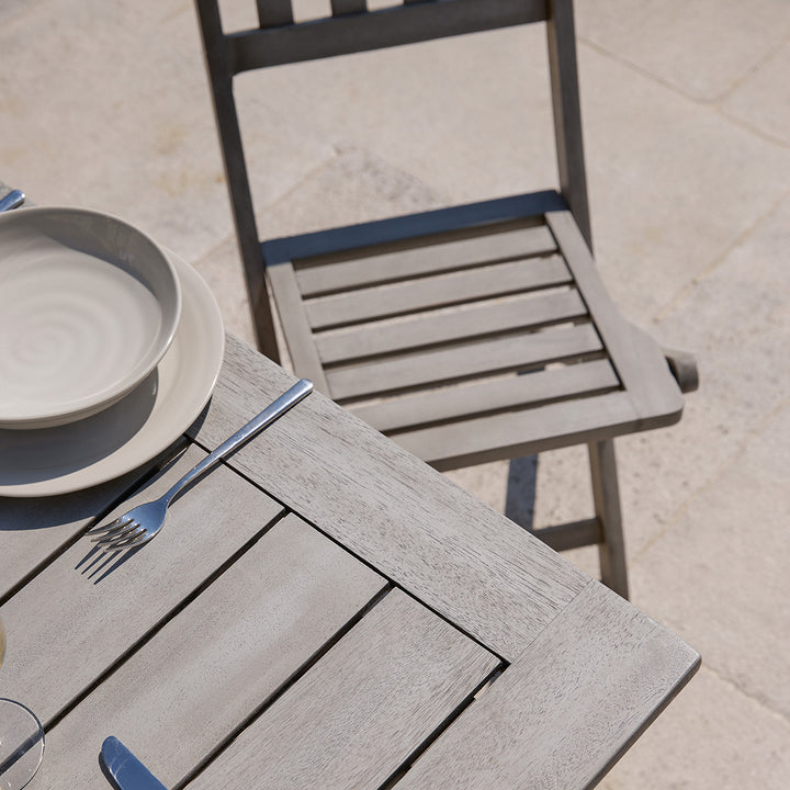 Corner of slatted wooden dining table and matching chair from the Repton garden set, styled for outdoor dining.
