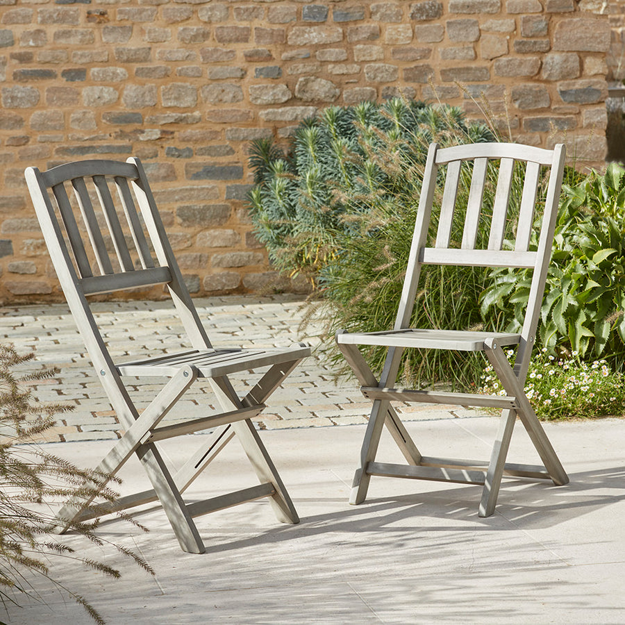 Pair of classic wooden folding bistro chairs styled outdoors on a patio.
