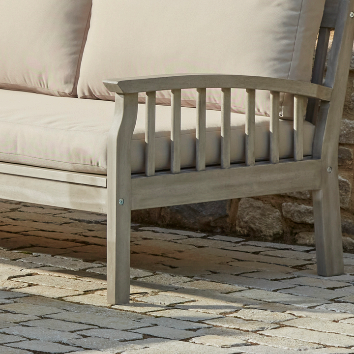 Close-up of the Repton Classic Wooden Garden Sofa armrest, showcasing its elegant slatted design and weather-resistant eucalyptus wood frame. The neutral beige cushions provide comfort and style, making it a perfect addition to outdoor patios and garden seating areas.