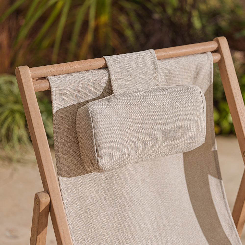 Beige cushion with pillow on a wooden chair against a blurred natural background