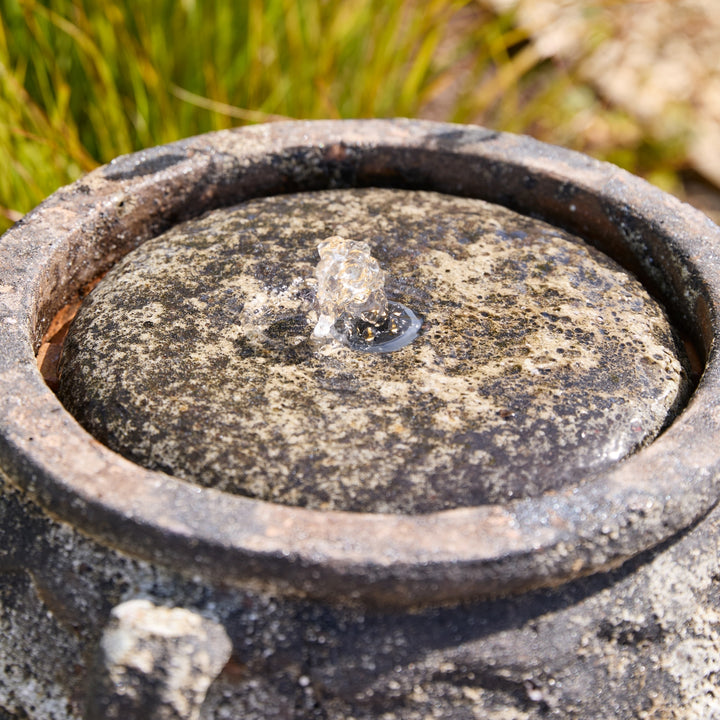 Close-up of a water feature textured stone surface with a natural outdoor background