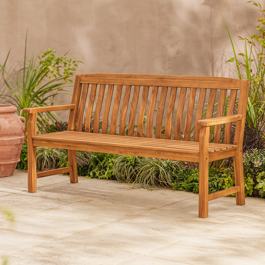 Wooden bench on a patio with plants in the background