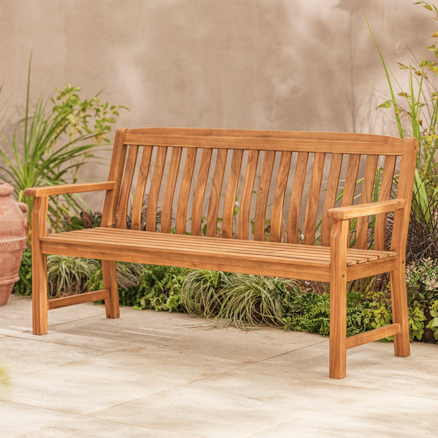 Wooden bench on a patio with plants in the background